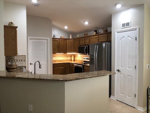 kitchen with sink, decorative backsplash, dark stone countertops, kitchen peninsula, and stainless steel appliances