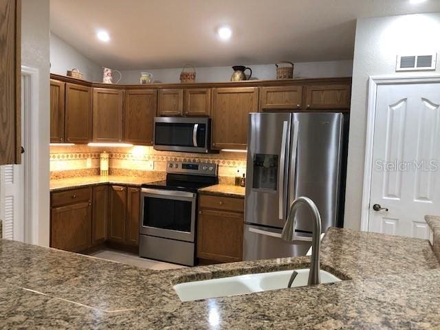 kitchen with decorative backsplash, sink, and stainless steel appliances