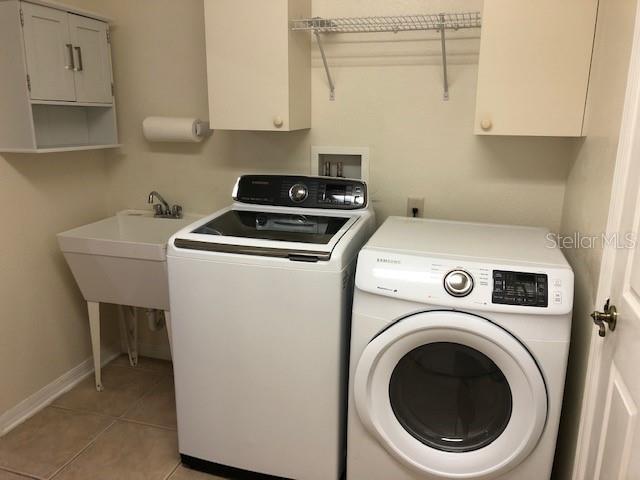 laundry room with cabinets, washer and clothes dryer, and light tile patterned flooring