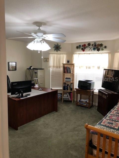 carpeted office featuring ceiling fan