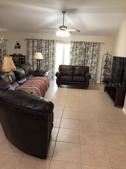 tiled living room featuring ceiling fan