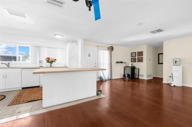 kitchen with white cabinetry, dishwasher, a center island, sink, and hardwood / wood-style floors