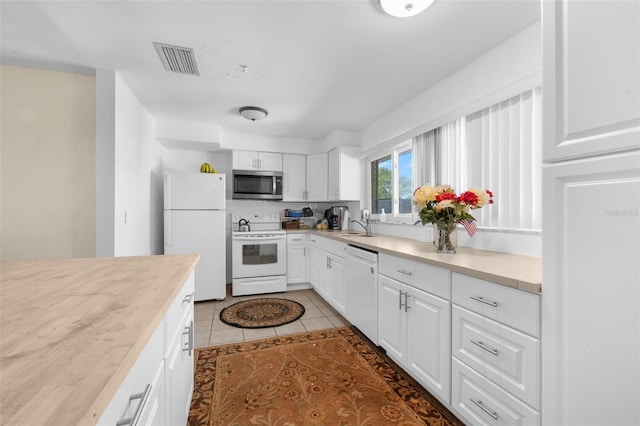 kitchen with white cabinetry, light tile patterned flooring, and white appliances