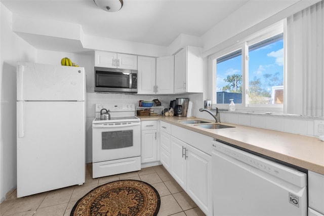 kitchen featuring white appliances, backsplash, sink, light tile patterned flooring, and white cabinetry