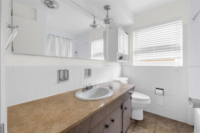 bathroom featuring toilet, vanity, tile patterned floors, and tile walls