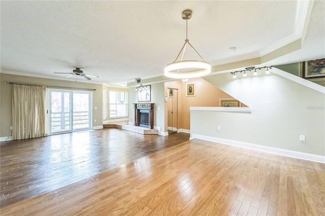 unfurnished living room with ornamental molding, a tile fireplace, a textured ceiling, and wood finished floors