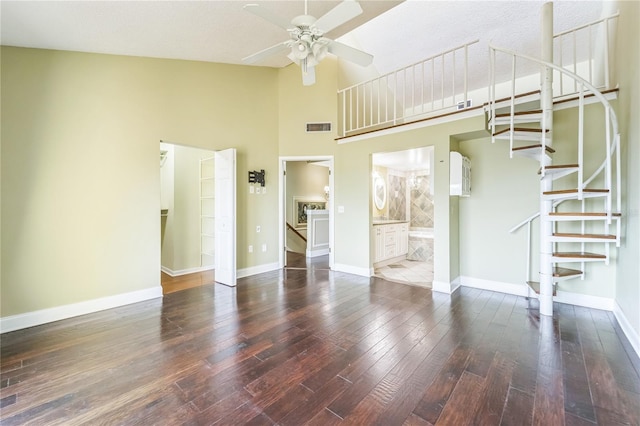 unfurnished living room featuring baseboards, visible vents, a ceiling fan, stairway, and dark wood-type flooring