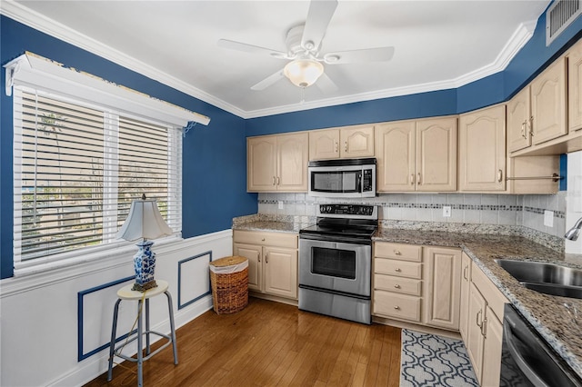 kitchen featuring dark wood-style flooring, crown molding, stainless steel appliances, visible vents, and a sink