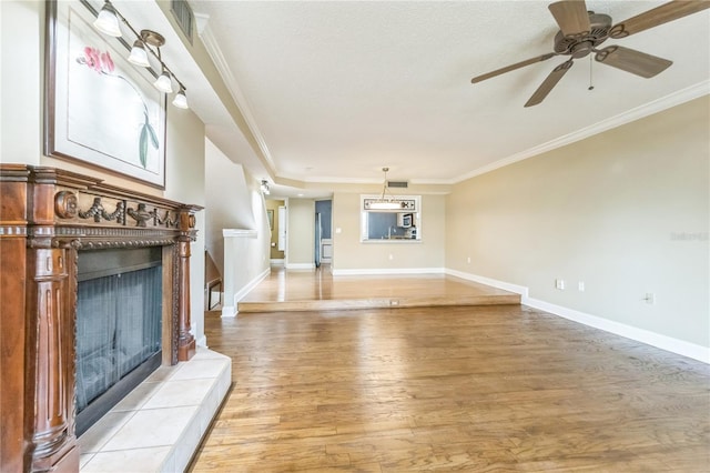 unfurnished living room with light wood-style floors, baseboards, ornamental molding, and a tile fireplace