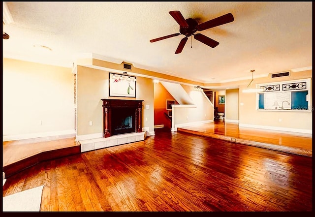 1710 Lighthouse Ter S Unit 1, South Pasadena, FL 33707 - unfurnished living room featuring a textured ceiling, wood finished floors, ceiling fan, a tiled fireplace, and visible vents
