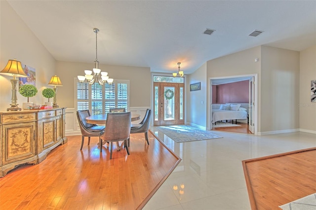 dining space with vaulted ceiling, light hardwood / wood-style floors, and an inviting chandelier