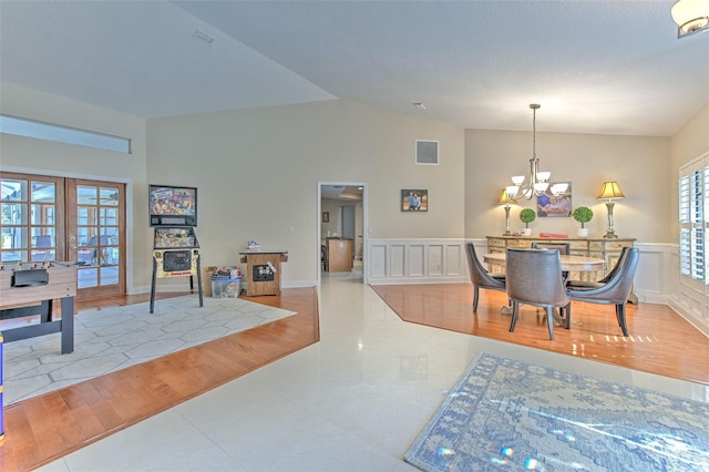 dining space featuring french doors, vaulted ceiling, an inviting chandelier, and light hardwood / wood-style flooring