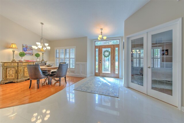 foyer featuring french doors, an inviting chandelier, lofted ceiling, and light tile patterned flooring