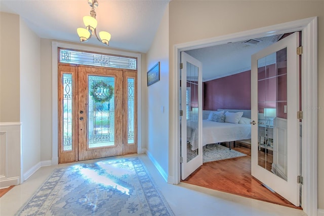 entrance foyer featuring a wealth of natural light, french doors, light hardwood / wood-style floors, and a notable chandelier