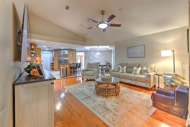 living room with ceiling fan, lofted ceiling, and light wood-type flooring