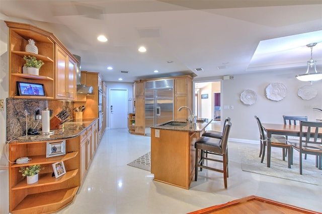 kitchen with sink, a kitchen breakfast bar, built in fridge, backsplash, and pendant lighting