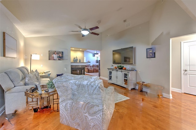 living room featuring ceiling fan, light hardwood / wood-style flooring, and vaulted ceiling