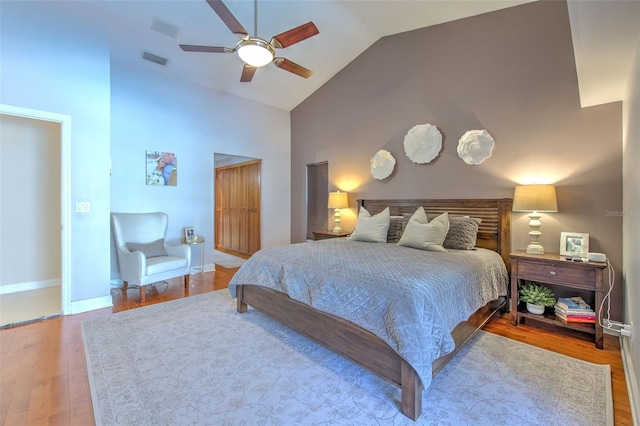 bedroom with ceiling fan, hardwood / wood-style floors, and vaulted ceiling