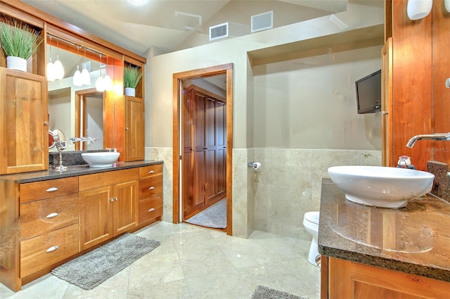 bathroom featuring vanity, toilet, lofted ceiling, and tile walls