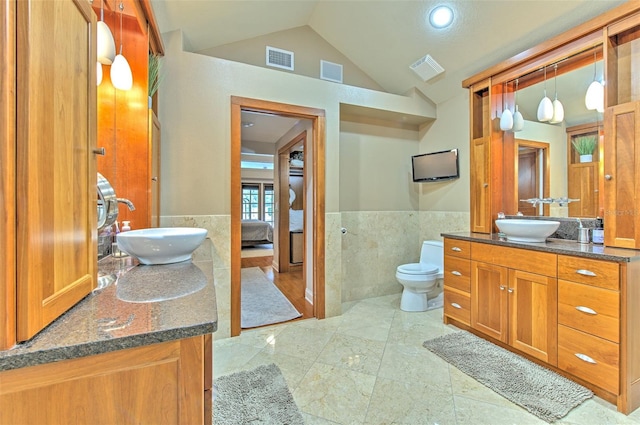 bathroom featuring vanity, toilet, lofted ceiling, and tile walls