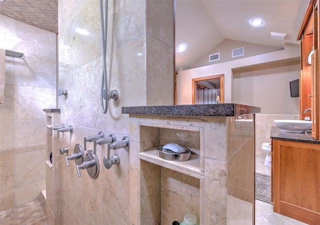 bathroom featuring tile patterned flooring, vanity, lofted ceiling, and tiled shower