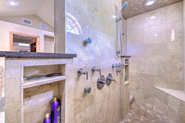 bathroom with lofted ceiling and tiled shower