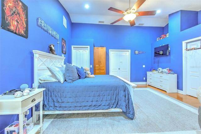 bedroom featuring ceiling fan, a closet, a towering ceiling, and wood-type flooring