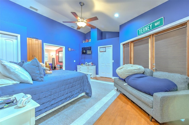 bedroom with hardwood / wood-style floors, ceiling fan, high vaulted ceiling, and two closets