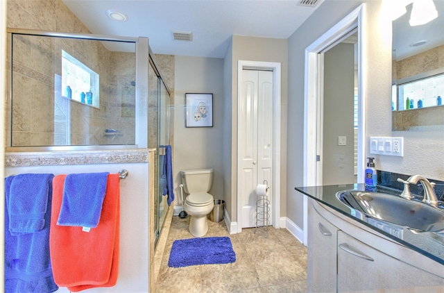 bathroom with tile patterned floors, vanity, an enclosed shower, and toilet