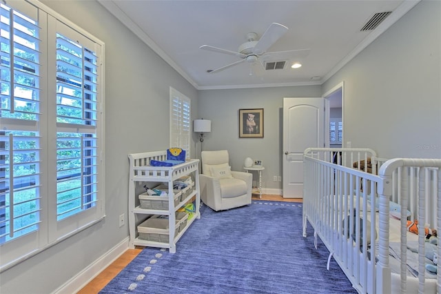 bedroom featuring multiple windows, ceiling fan, dark hardwood / wood-style flooring, and a crib