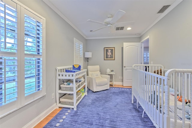 bedroom with a nursery area, ceiling fan, dark hardwood / wood-style flooring, and multiple windows