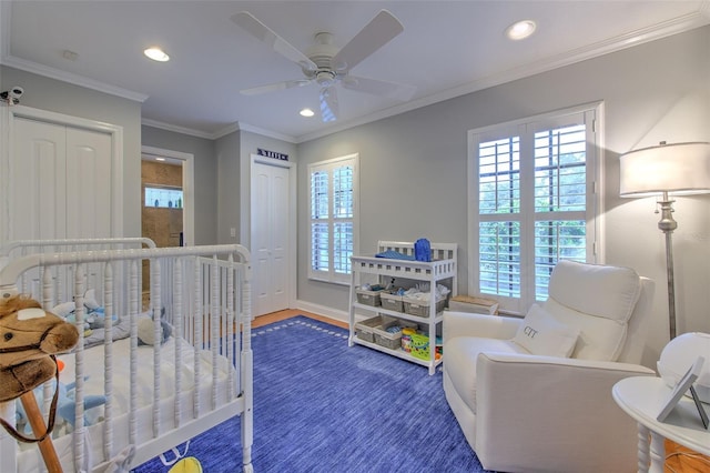 bedroom featuring ornamental molding, ceiling fan, dark wood-type flooring, a crib, and a closet