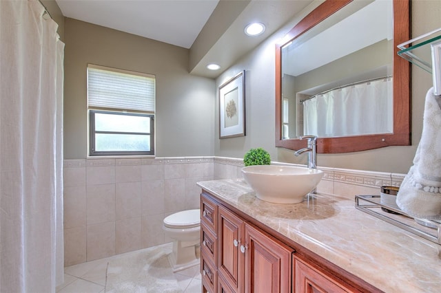 bathroom featuring tile patterned flooring, vanity, toilet, and tile walls