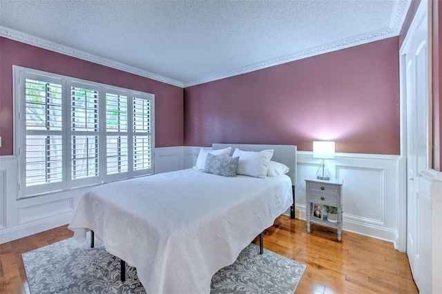 bedroom with light hardwood / wood-style floors, a textured ceiling, and ornamental molding