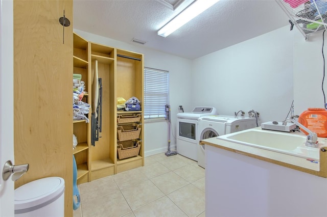 laundry room with independent washer and dryer, a textured ceiling, light tile patterned floors, and sink