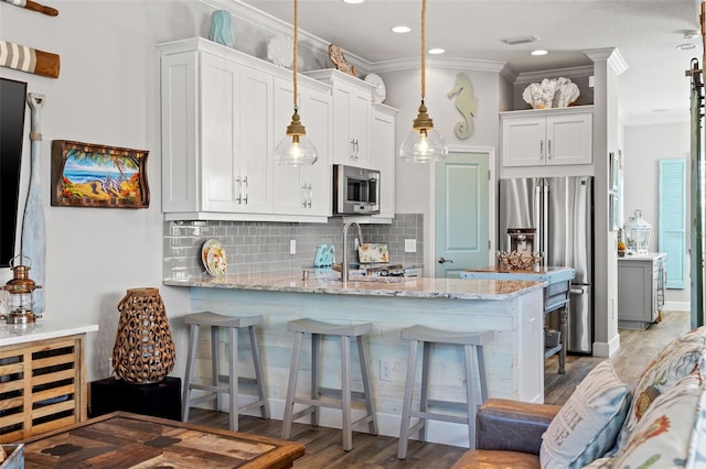 kitchen with light stone countertops, appliances with stainless steel finishes, a breakfast bar, light hardwood / wood-style floors, and white cabinetry