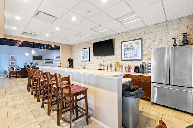 kitchen with pendant lighting, a breakfast bar, light tile patterned floors, and stainless steel refrigerator