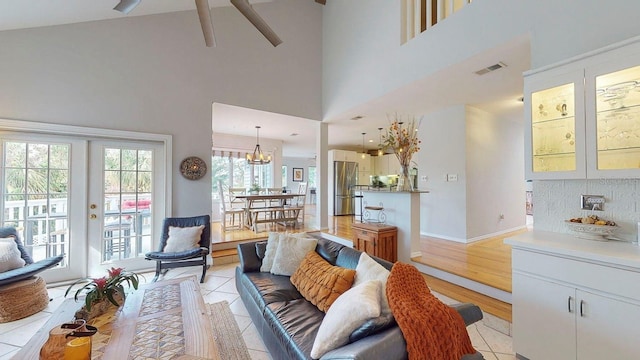 living room featuring ceiling fan, light wood-type flooring, high vaulted ceiling, and french doors