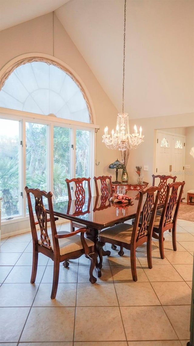 dining area featuring light tile patterned floors, high vaulted ceiling, and an inviting chandelier