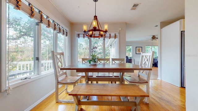 dining space featuring light wood-type flooring, a wealth of natural light, and ornamental molding