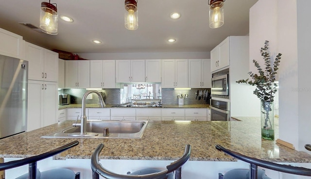 kitchen with a kitchen breakfast bar, white cabinetry, pendant lighting, and appliances with stainless steel finishes