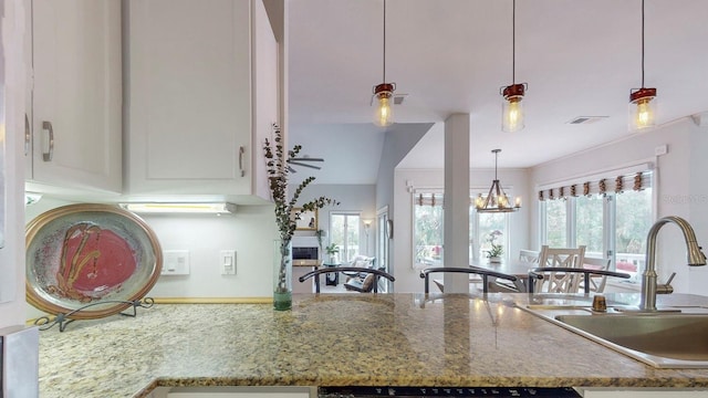 kitchen with hanging light fixtures, sink, a chandelier, and stone countertops