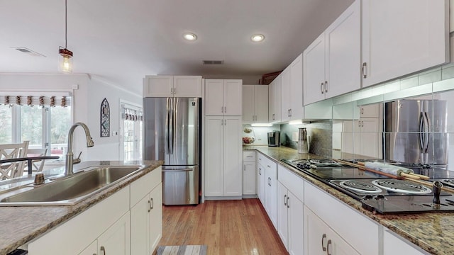 kitchen featuring stainless steel fridge, cooktop, sink, white cabinets, and light hardwood / wood-style floors