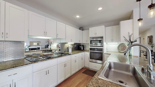 kitchen with stainless steel appliances, white cabinetry, and sink