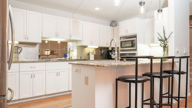 kitchen featuring stone countertops, light hardwood / wood-style floors, white cabinetry, and stainless steel appliances