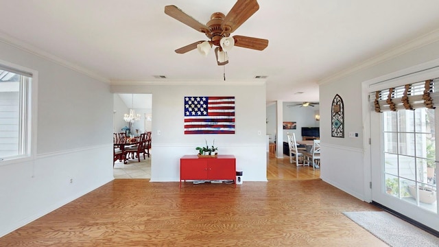 interior space featuring ceiling fan with notable chandelier, light wood-type flooring, and crown molding