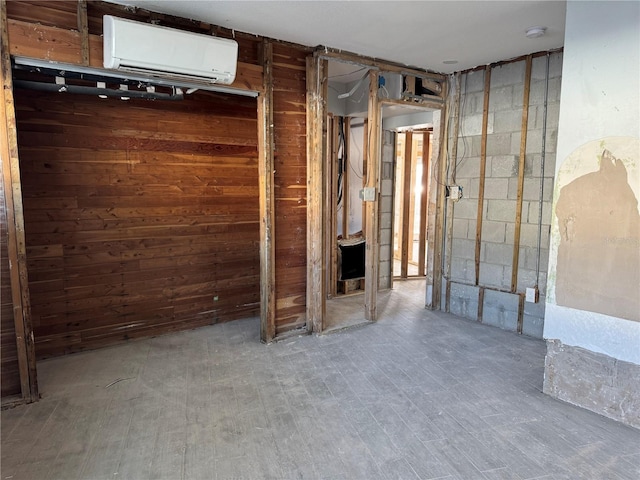 empty room with wood walls, a wall mounted air conditioner, and concrete block wall