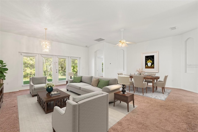 living room featuring light carpet and ceiling fan with notable chandelier