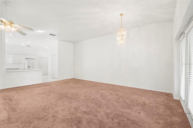 carpeted spare room with ceiling fan with notable chandelier