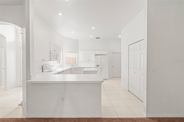 kitchen featuring white appliances, white cabinets, sink, light tile patterned floors, and kitchen peninsula